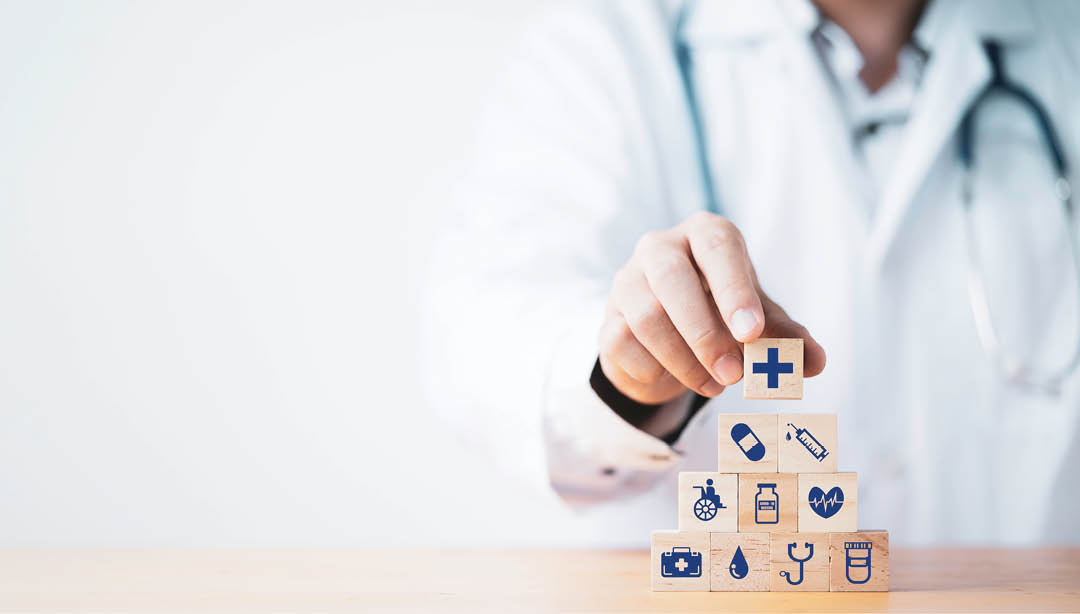 A person wearing a white lab coat is holding up a block with a medical symbol on it. AI generated content