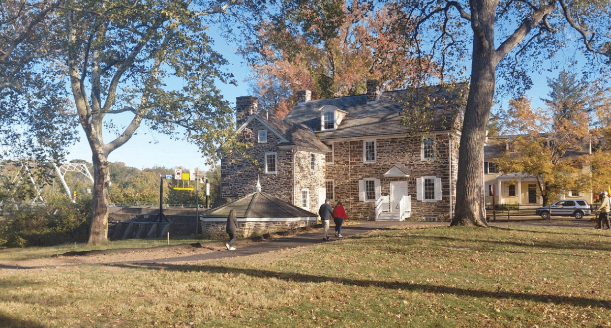 A group of people walking on a sidewalk in front of a house. Description generated by AI