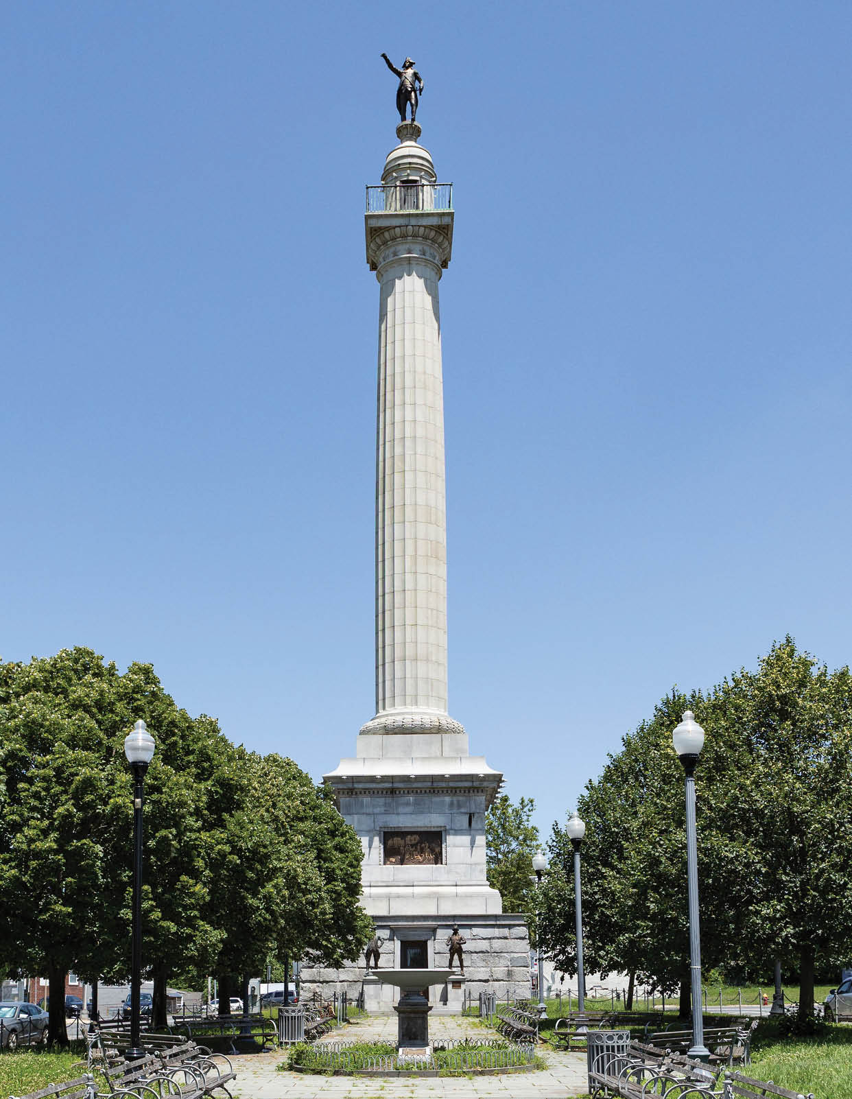 A tall white monument with a statue on top. Description generated by AI