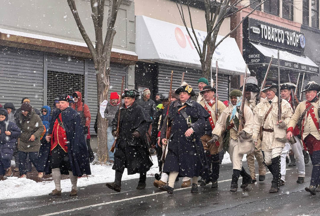 A group of people walking down a street in the snow. Description generated by AI