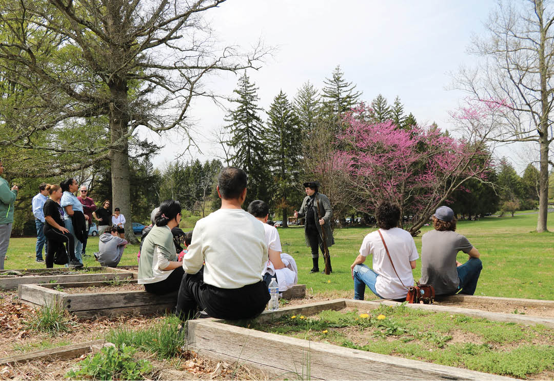 A group of people sitting on the ground in a park. Description generated by AI