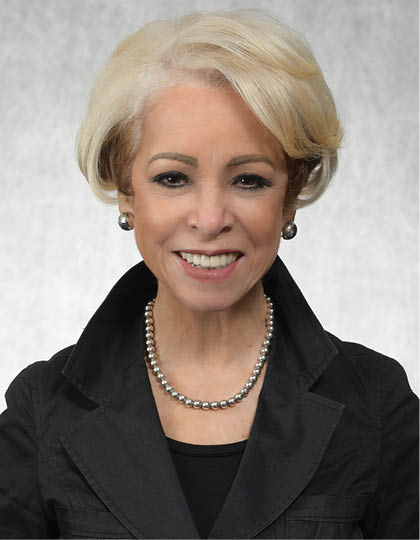 A woman wearing a green jacket and a green shirt is smiling for the camera. AI generated content