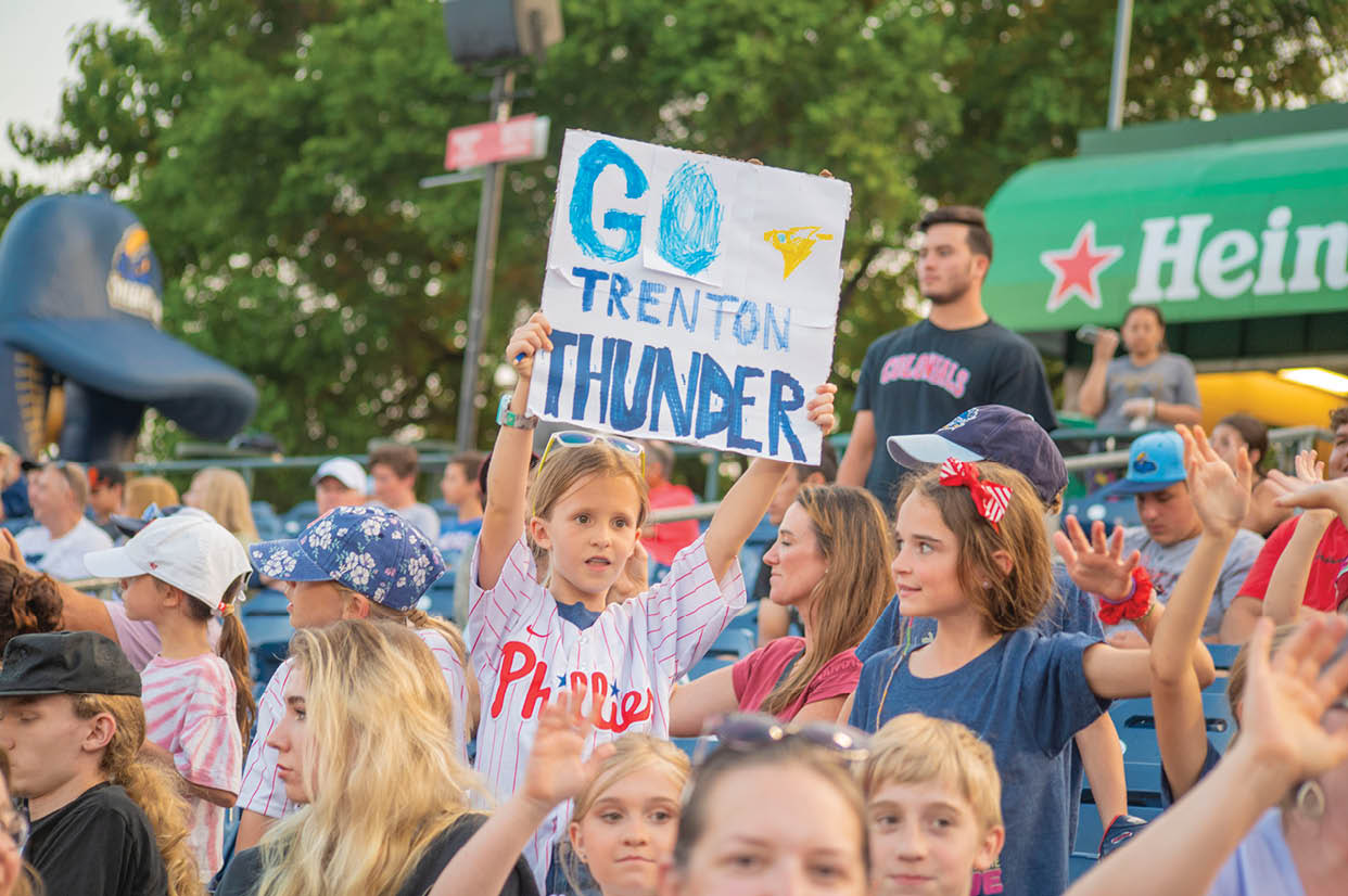 A young girl holds a sign that says Go Thunder. Description generated by AI
