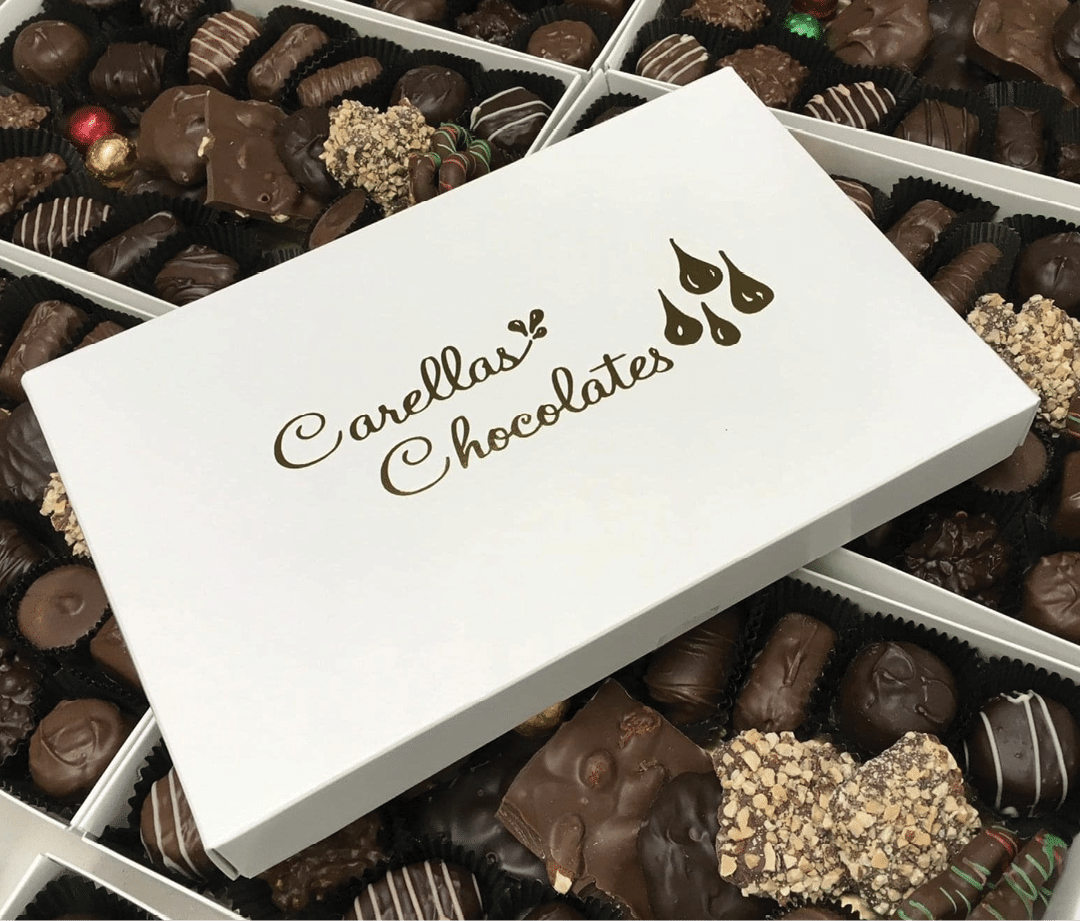 A box of chocolates with a white box and gold lettering. Description generated by AI
