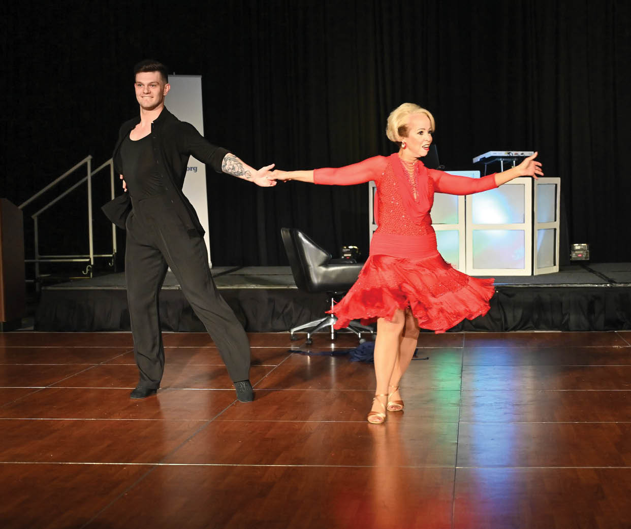 A man and woman are dancing on a stage. Description generated by AI
