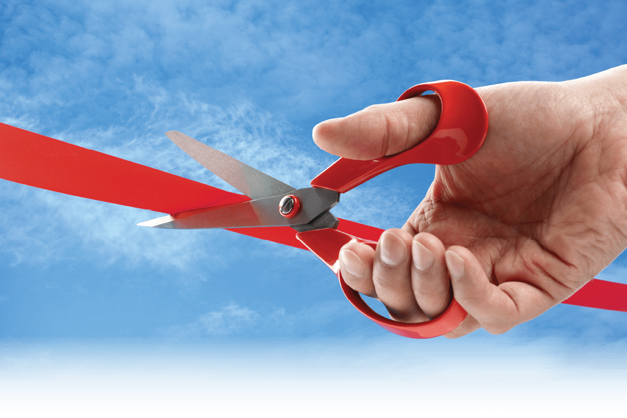 Businessman cutting a red ribbon with a pair of scissors