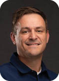 A man wearing a blue shirt and white undershirt. Description generated by AI
