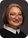 A woman wearing a black shirt and glasses. Description generated by AI