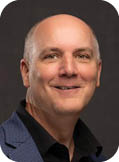 A man wearing a blue jacket and black shirt. Description generated by AI