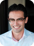 A man wearing glasses and a blue shirt. Description generated by AI