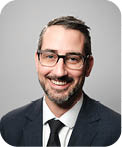 A man wearing a suit and tie with a black tie. Description generated by AI