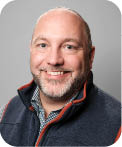 A man wearing a blue and red vest. Description generated by AI