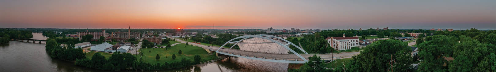 A beautiful sunset over a river with a bridge in the background. Description generated by AI