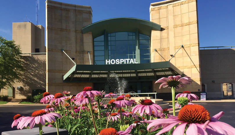A hospital building with a water fountain in front. AI generated content