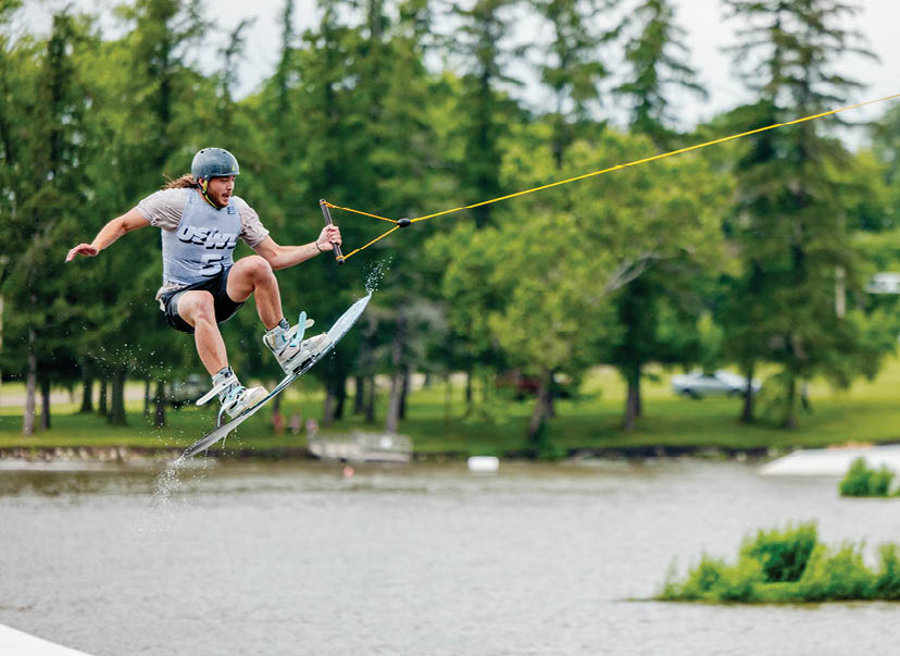 A man is performing a trick on a snowboard, jumping over the water. AI generated content