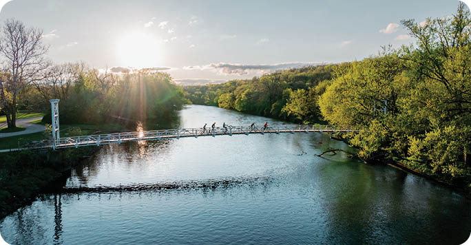 A group of people are walking across a bridge over a river. AI generated content
