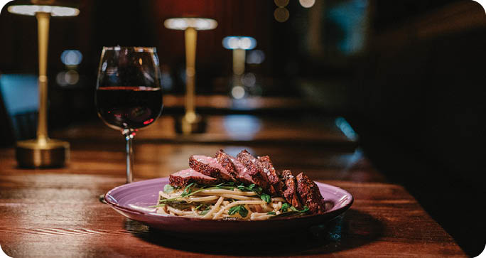 A plate of food with a glass of wine on a table. Description generated by AI