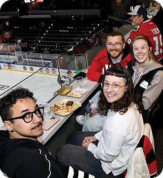 A group of people are sitting at a table in a stadium. Description generated by AI