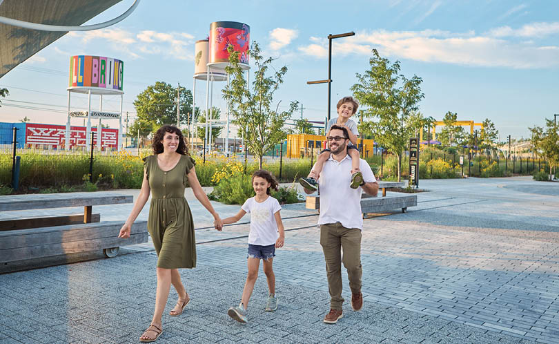 A family of four, including a man, a woman, and two children, are walking together in a city park. AI generated content
