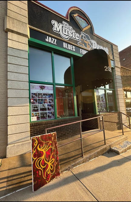 A storefront with a sign that says “The Music Joint" and a painting of a fire on the sidewalk. AI generated content