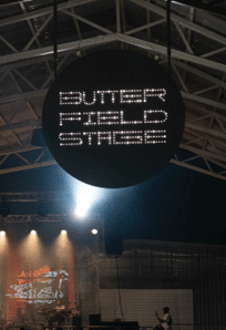 A stage with a sign that says “Butter Field Stage" and a person standing on it. AI generated content