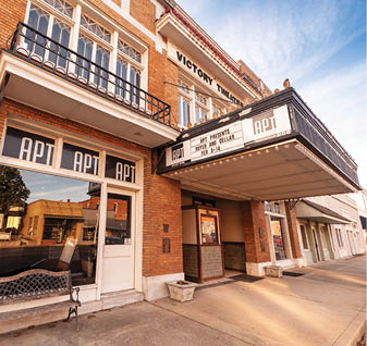 A theater marquee is displayed on the side of a brick building. AI generated content