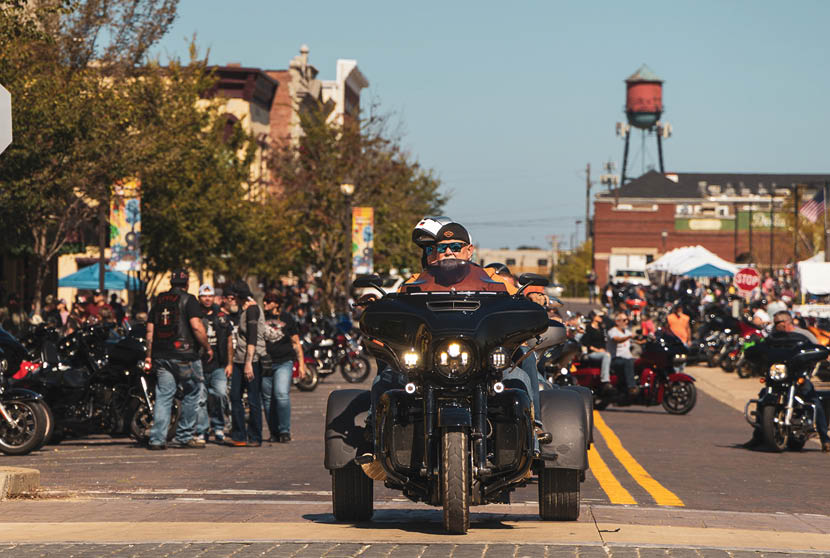 A black motorcycle with a sidecar is driving down a street. Description generated by AI