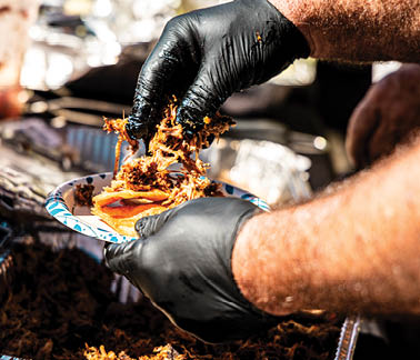 A person wearing black gloves is scooping food from a tray. AI generated content