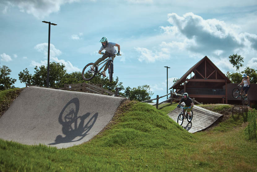 A man is riding a bike on a ramp, performing a trick. Another man is watching from the top of the ramp. AI generated content