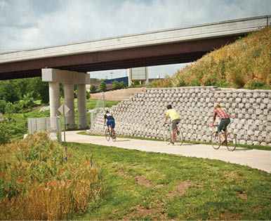 Three people are riding bicycles on a path near a bridge. AI generated content