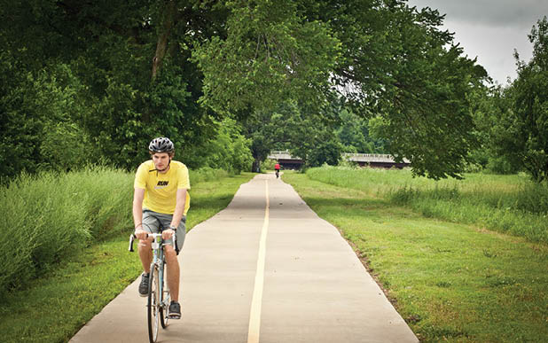 A man riding a bike on a path with trees in the background. AI generated content