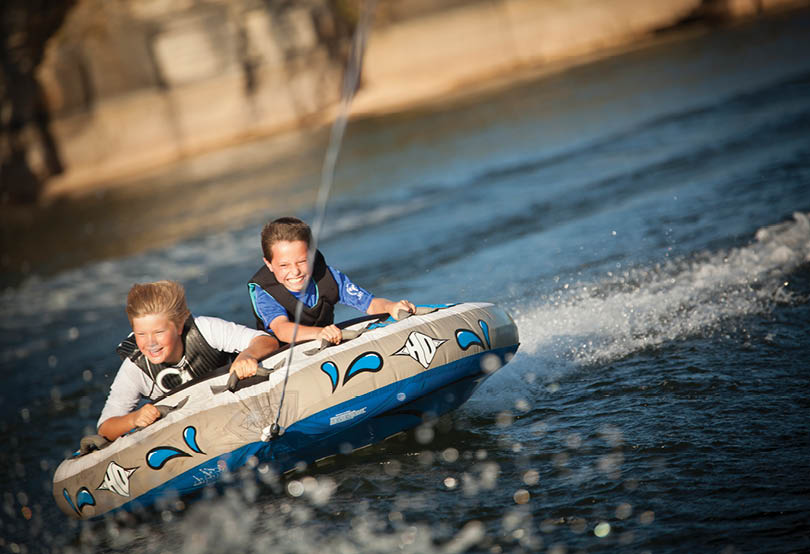 Two boys are riding a blue and white watercraft on a body of water. AI generated content