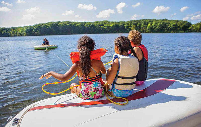 Three children are sitting on a boat. Description generated by AI