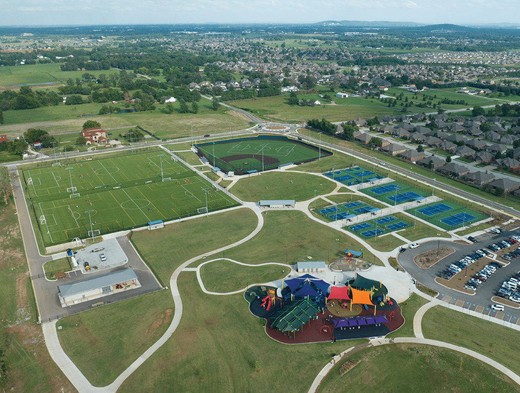 A large grassy field with a baseball diamond in the middle. Description generated by AI