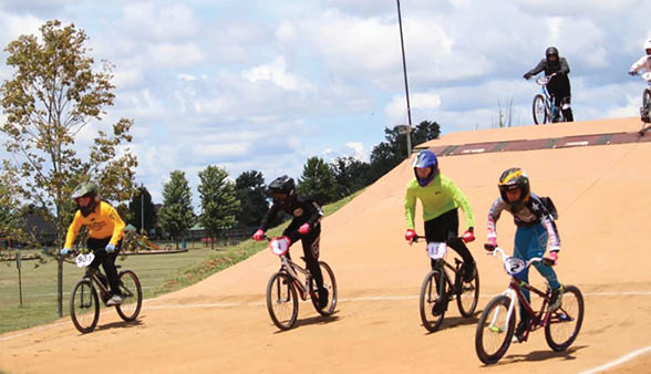 A group of people riding bikes on a dirt track. Description generated by AI