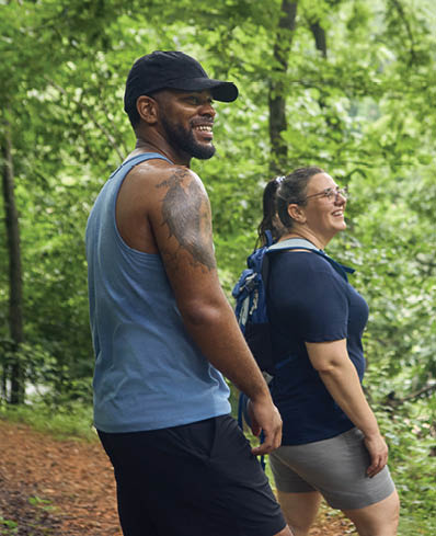 A man and woman are walking in the woods. Description generated by AI