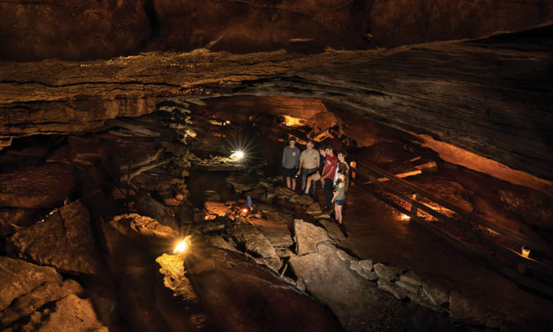 A group of people are standing in a cave, looking at a light. AI generated content