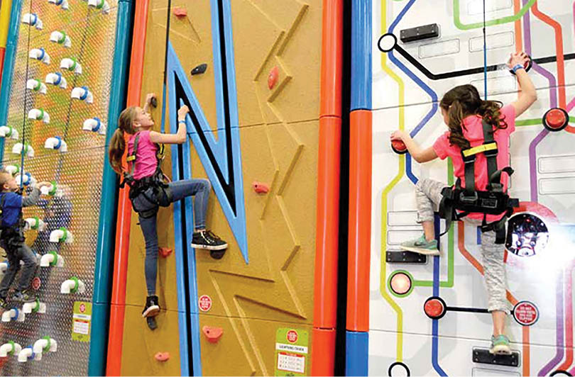A girl is climbing a wall with a pink shirt on. Description generated by AI