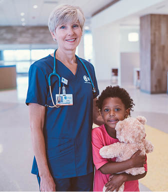 A woman in a blue shirt and a child are standing in a hallway. The woman is holding a teddy bear. AI generated content