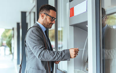 A man in a suit is using a cash machine. AI generated content