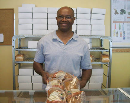 A man is standing in front of a display case filled with various types of bread. AI generated content