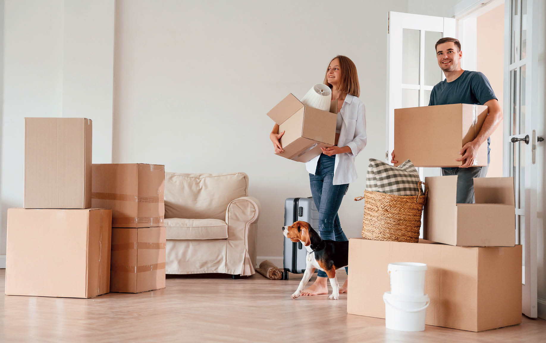 Walking forward with boxes. Young couple with dog are moving to new home.