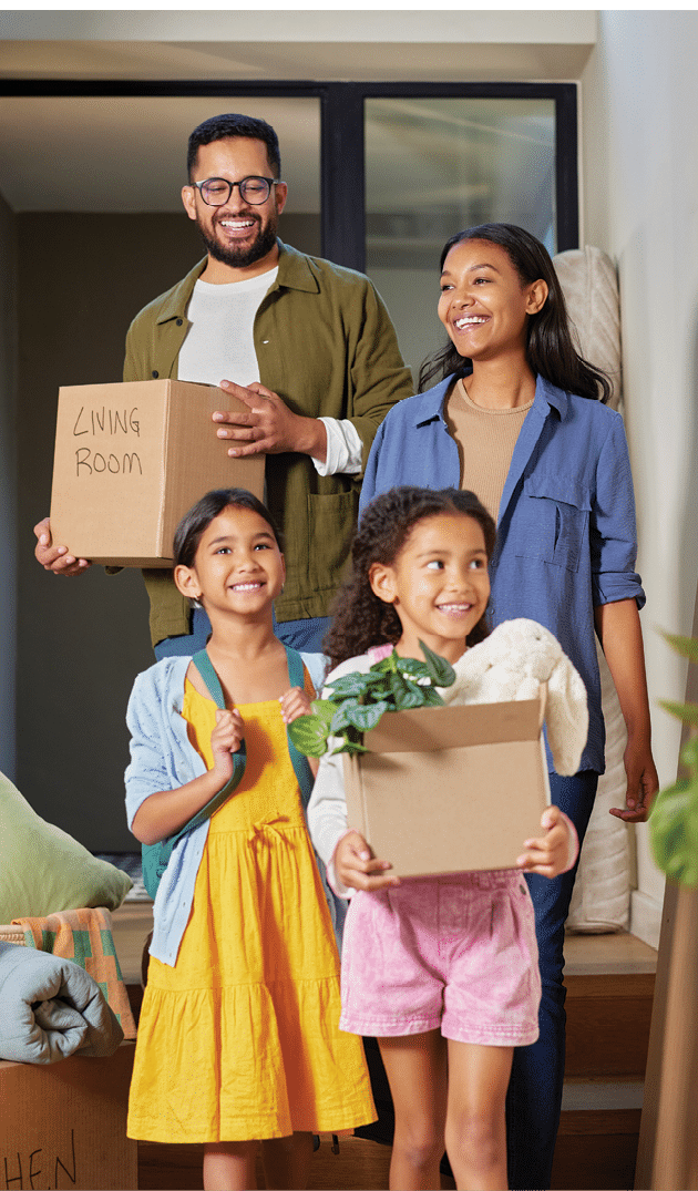 Happy mixed race family moving into a new home together. Middle eastern parents and children carrying boxes with smiles in new apartment. Happy smiling daughters helping mother and father with cardboard boxes in new house on moving day.