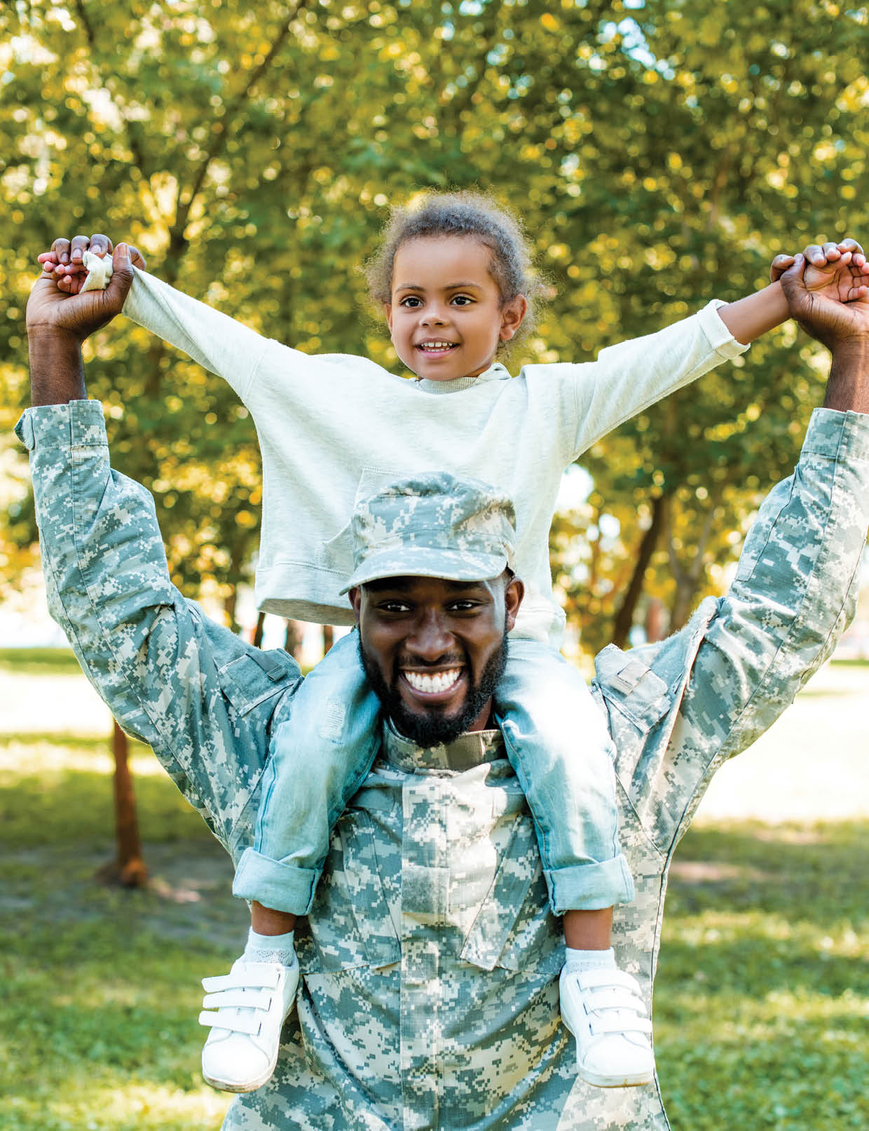 happy african american soldier in military uniform holding daughter on shoulders in park
