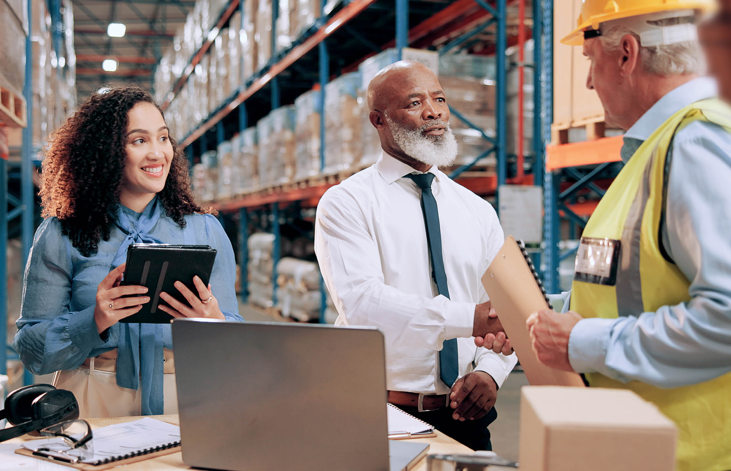 Business people, document and handshake in warehouse for logistics, meeting for supply chain collaboration. Import team, tech or shaking hands in storage for export deal, service agreement or welcome