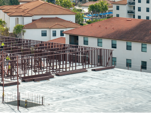 Workers assembling metal frame building at industrial construction site. Housing development in America. Real estate market in the USA.
