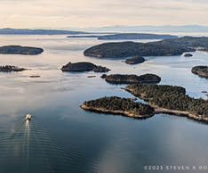 A boat on the water in front of a group of islands. Description generated by AI