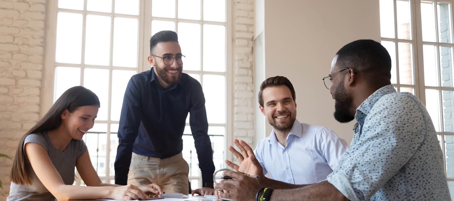 Smiling arabian team leader with colleagues listening to african american male manager, telling funny story or joke  Joyful multiracial business people partners laughing, having fun during break time 