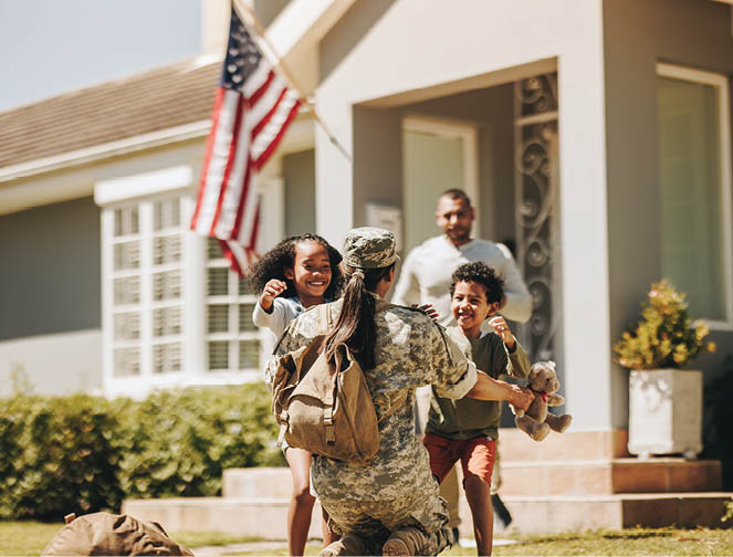 Servicewoman embracing her children after arriving home from the army. American soldier receiving a warm welcome from her husband and kids. Military woman reuniting with her family.