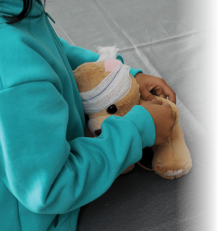 4-year-old brunette Latina girl with glasses represents mistreatment and physical abuse in her teddy bear with bandages on her head